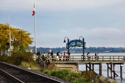 a group of people standing on a pier near the water at Beach Breeze White Rock in White Rock
