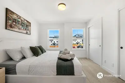 a white bedroom with a bed and two windows at Modern Luxury Townhome near Aspen Landing and Winsport in Calgary