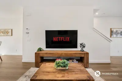 a living room with a tv and a wooden table at Modern Luxury Townhome near Aspen Landing and Winsport in Calgary