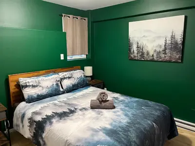 a bedroom with a bed with a green wall at Lake View Suite, Forest Retreat, Balfour BC in Balfour