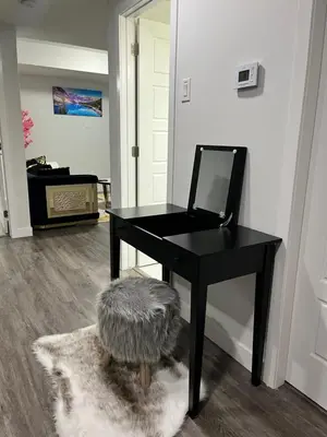 a black desk with a mirror and a furry stool at One bedroom private entrance suite in Edmonton