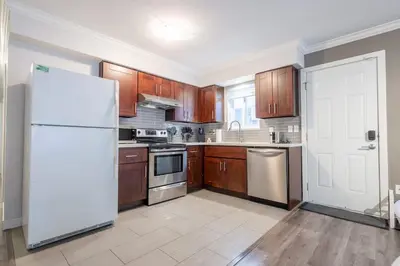 a kitchen with wooden cabinets and a white refrigerator at Sleek Modern Escape Suite - Comfort and Style in the City in Vancouver