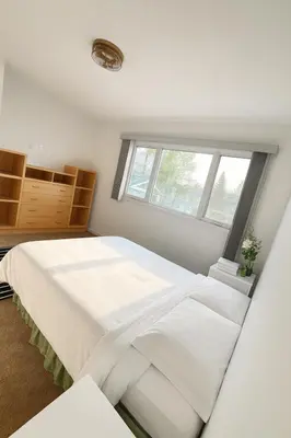 a white bedroom with a large bed and a window at Great Northern Escapes - The Managers House in Yellowknife