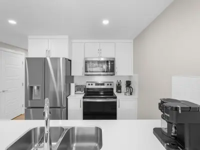 a white kitchen with a stove and a refrigerator at Exquisite 1-Bdr Condo Apt in Calgary