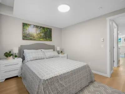 a white bedroom with a bed and a painting on the wall at Exquisite 1-Bdr Condo Apt in Calgary