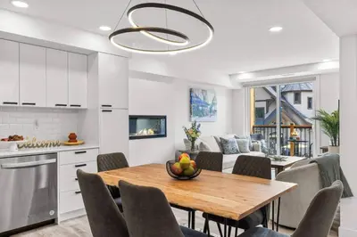 a kitchen and living room with a wooden table and chairs at Newly Built 2BR and 2BA MtnView Retreat in DT Canmore in Canmore