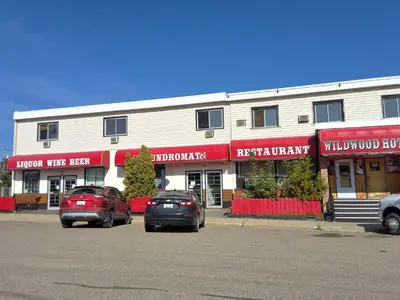 two cars parked in a parking lot in front of a building at Wildwood Hotel in Wildwood