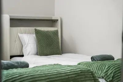 a bed with green and white sheets and pillows at Private Sherwood Suite by Park in Calgary