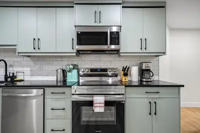 a kitchen with white cabinets and stainless steel appliances at Private Sherwood Suite by Park in Calgary
