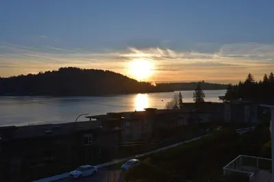 a sunset over a river with the sun in the sky at Casa del Mar Villa in North Vancouver