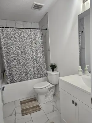 a bathroom with a toilet and a shower curtain at Non Smoking- Stylish Basement Suite Near Airport, Trails & Dining in Edmonton