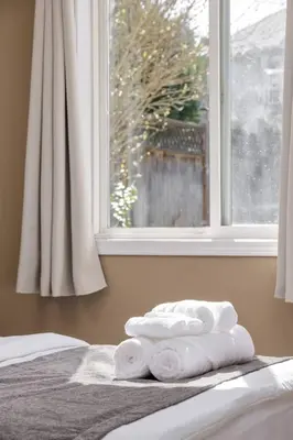 a group of towels sitting on a bed in front of a window at Cozy and Relaxing Private Getaway Free Parking in Nanaimo