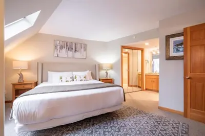 a bedroom with a large white bed and a bathroom at Marquise 610 by Outpost Whistler in Whistler