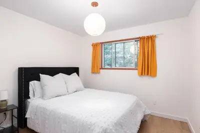 a bedroom with a white bed and a window at Ocean Vista In the Woods on Saltspring Island in Salt Spring Island