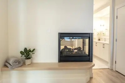 a fireplace in a living room with white walls at High Tide Suite - New Bright Oceanfront Escape with Spa-like Bath in Nanoose Bay
