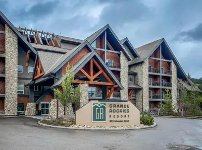 a large building with a sign in front of it at Cozy King Condo Mountain Views, Resort Perk and BBQ in Canmore