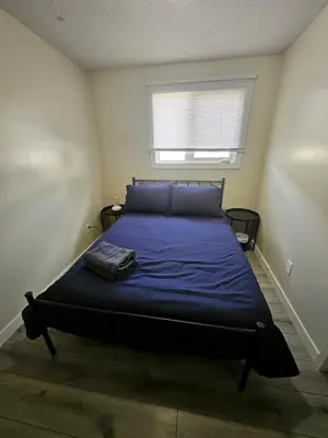 a bedroom with a bed with blue sheets and a window at The Onyx Suite In Inglewood Minutes To DT in Calgary