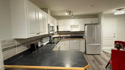 a kitchen with white cabinets and a refrigerator at Main Floor Condo Fully Independent 1 Bed 1 Bath in Edmonton