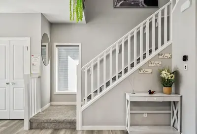 a white staircase in a home with a white table at Cozy 3-Bedroom Family Retreat Home in Rangeview in Calgary