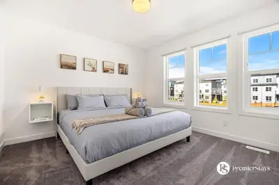 a bedroom with a bed and two windows at Luxurious Designer Finished Home in Calgary