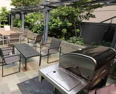 a barbecue grill on a patio with chairs and tables at Cozy Condo in the heart of the city in Vancouver