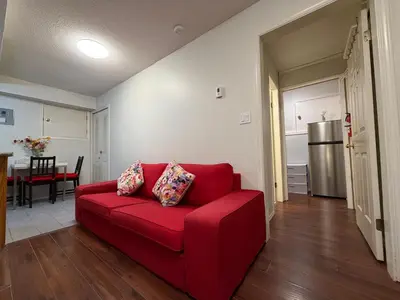 a red couch in a living room with a kitchen at Lovely suite in Burnaby