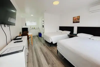 a bedroom with two beds and a desk with a tv at Westview Centre Motel Ltd in Powell River
