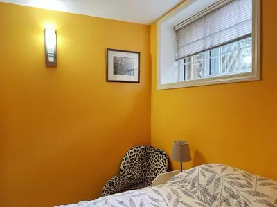 a bedroom with yellow walls and a bed and a window at UBC Two-Bedroom Suite - Steps from Beach, Park & Golf - Full Kitchen in Vancouver
