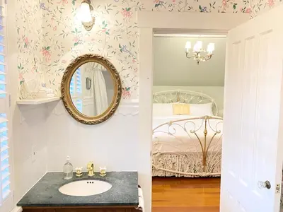 a bathroom with a sink and a mirror and a bed at Princess and the Pea Hotel in Langley