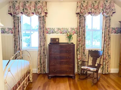 a bedroom with a dresser and two windows at Princess and the Pea Hotel in Langley