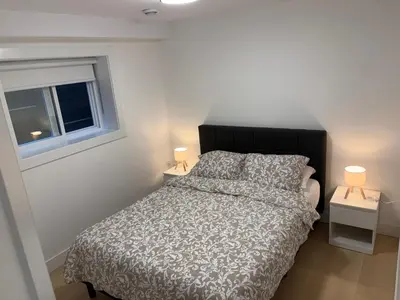 a bedroom with a bed and a window and two lamps at Cozy Private Suite in Langley in Langley