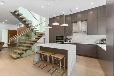 a kitchen with a staircase and a counter with stools at New Lux House on Vancouver West in Vancouver