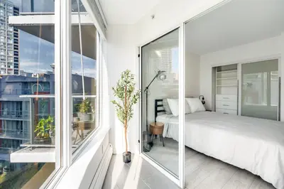 a bedroom with a bed and large windows at Modern Condo in Downtown Vancouver in Vancouver