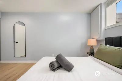 a bedroom with a white bed and a mirror at Spacious Cozy Couples Getaway Basement Suite in Sundance in Calgary