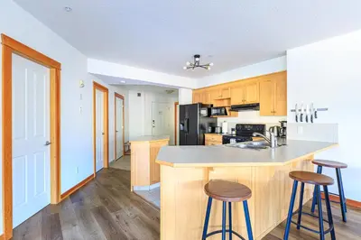a kitchen with wooden cabinets and a counter with stools at Bluebird - Spacious Luxury Shared Rooftop Hot Tub in Canmore