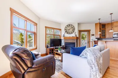 a living room with a couch and a clock on the wall at McAuley Manor - Mountain Views Downtown Location in Canmore