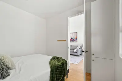 a white bedroom with a bed and a mirror at The Sunny 2 Suites 10 Pax Pet Friendly Stay in Calgary