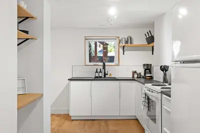 a white kitchen with white cabinets and a stove at The Sunday Charming Private Suite in Calgary in Calgary