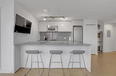 a kitchen with three bar stools at a counter at Urban Calm, Comfort in the Heart of the City in Vancouver
