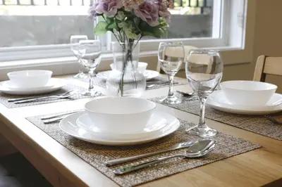 a table with plates and glasses and a vase with flowers at Cozy 2BR for Family & Private Parking & Near Mall in Langley