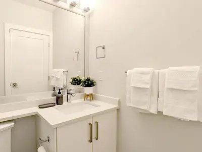 a white bathroom with a sink and a mirror at Cozy 2BR for Family & Private Parking & Near Mall in Langley