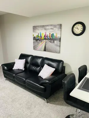 a black leather couch in a room with a clock at Modern 2-bed 1-bath Suite in Calgary