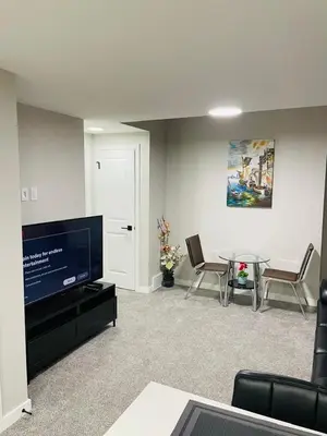 a living room with a flat screen tv and a table at Modern 2-bed 1-bath Suite in Calgary