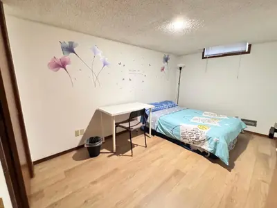 a bedroom with a bed and a desk and a wall with butterflies at Only 7 km from YYC Sandstone Homestay in Calgary