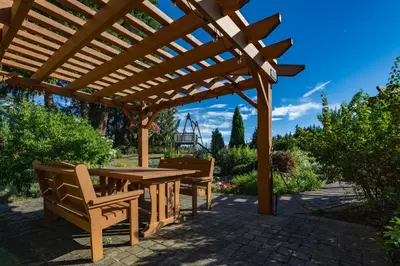 a wooden pergola with a wooden table and benches at Ackerview Guesthouse Bed and Breakfast in Salmon Arm