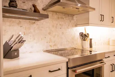 a kitchen with white cabinets and a stove top oven at Luxury Spring Creek Condo with Hot Tub in Canmore