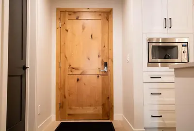 a wooden door in a kitchen next to a microwave at Luxury Spring Creek Condo with Hot Tub in Canmore