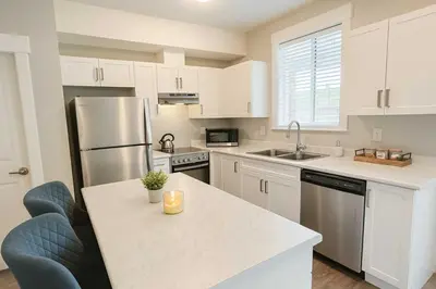 a kitchen with white cabinets and a stainless steel refrigerator at Bright & Modern 1-Bedroom Guest Suite in Chilliwack