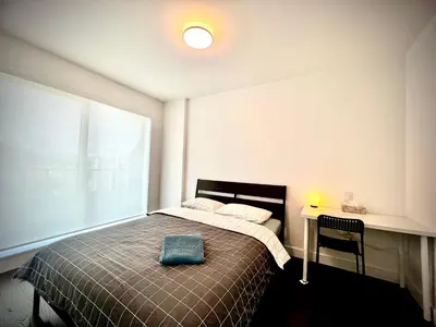 a bedroom with a bed and a table and a window at Mordern stylish 2B2B close to Richmond center in Richmond