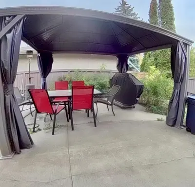 a patio with a table and chairs under a canopy at Beautiful Suite Fenced yard Kitchen Laundry in St. Albert